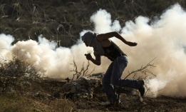 Палестински демонстрант бяга от сълзотворен газ, пуснат от израелски военни части по време на протест в петък, 2 декември.