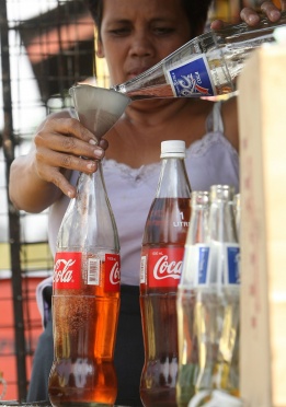 Филипинка продава бензин в бутилки от „Кока-Кола“ на сергията си в град Куезон, източно от Манила, Филипините, 13 декември.
