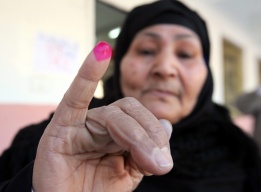 Възрастна жена показва мастилото, останало по пръста й, след като е гласувала на балотажа в третия рунд на парламентарните избори в Египет, Кайро, 10 януари.