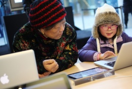 Баба и внуче разглеждат компютър MacBook в магазин на „Епъл“ в Пекин, Китай, 10 януари.