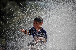 Дете си играе с вода на площад в Мексико Сити, Мексико.