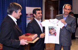 Президентът Махмуд Ахмадинеджад (в средата) позира с тениска с лика на убития ирански ядрен физик Мустафа Ахмади-Рошан в иранския Ден на атомната енергия.
