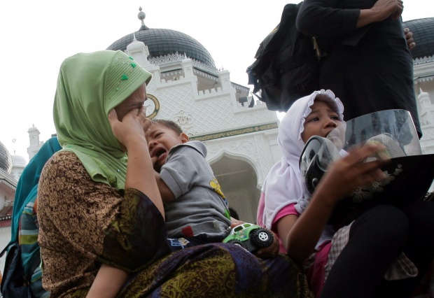 Майка, носеща сина си, плаче заедно с дъщеря си заради заплахата от цунами, която беше обявена в Индонезия след земетресението от 8.6 по Рихтер.