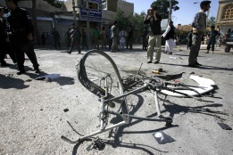 Полицай инспектира остатъци от колело на мястото на бомбена експлозия в афганистанския град Херат.