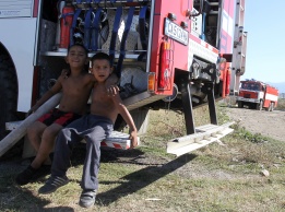 Деца от ромската махала в кв. Орландовци в София позират на фона на разразилия се на мястото  пожар.