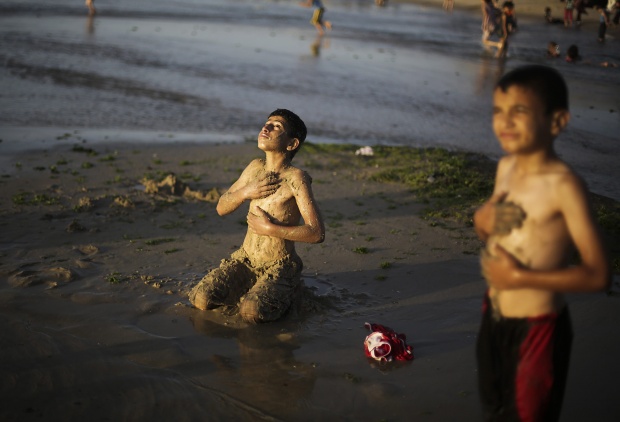 Палестинско момче е покрило тялото си с пясък, за да се предпази от гъбички, след като е плувало на плажа Деир Ал-Бала в ивицата Газа. Плажът облекчава гражданите на ивицата в жегите, където температурите достигнаха 31 градуса в четвъртък.