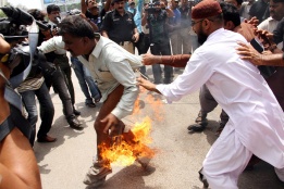 Служители на министерството на образованието в Пакистан се опитват да изгасят техен колега, самозапалил се в знак на протест срещу неизплащането на заплати в Карачи, Пакистан.
