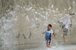 Момченце тича из изкуствен водопад в парк в Токио, за да се спаси от рекордните жеги в региона