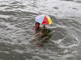 Филипинка се шегува, докато държи чадър, докато тайфунът Ютор бушува по брега на Манила, Филипините