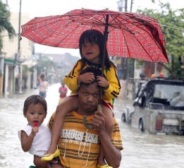 Филипинец пренася децата си през наводнена улица в Kawit town, южно от столицата Манила, където на места водата достига 2 метра