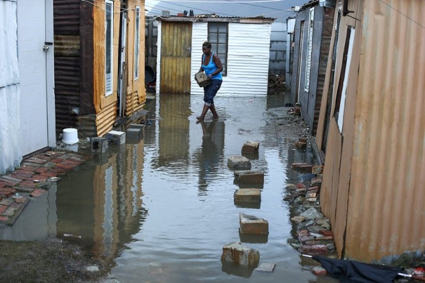 Жена се опитва да премине през наводнената улица в Кейп Таун, Южна Африка, където 3500 души бяха евакуирани заради поройните дъждове