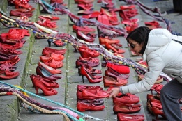 Италианка оставя чифт червени обувки на площад във Флоренция - символ на международната кампания "Извърви километър в нейните обувки", която цели равенство между половете и борба с насилието над жени