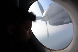 Човек поглежда през прозореца на самолет на Виетнамските военни сили, който издирва изчезналия на 8 март Малайзийски самолет с 239 души на борда