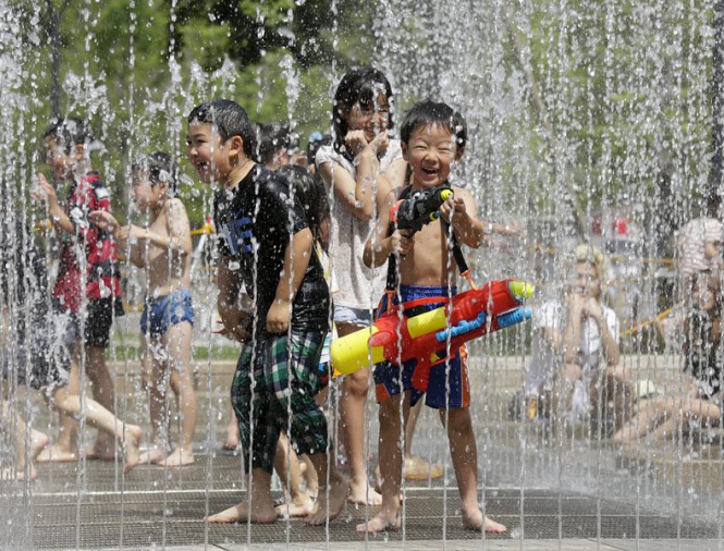 Деца си играят с водата, за да се охладят от големите жеги, които връхлетяха японската столица Токио