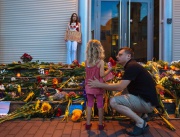 Баща и дъщеря поставят цветя в памет на загиналите жертви от катастрофиралия в Украйна боинг, пред момиче с надпис "Путин убиец" пред посолството на Холандия в Киев