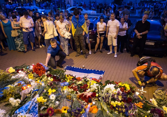 Хора поднасят своите съболезнования за загиналите стотици жертви в авиокатастрофата над Украйна, пред холандското посолство в Киев