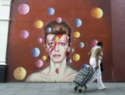 Жена минава покрай стенопис, изобразяващ британския музикант Дейвид Бауи в Южен Лондон, Великобритания.