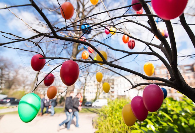 Минувачи се радват на окачени разноцветни яйца по дърветата в Хамбург, Германия