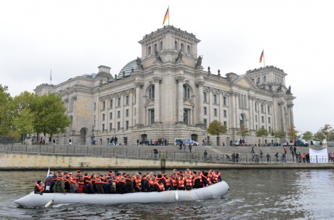 Германски парламентаристи преминават по реката Шпрее покрай Райхстага в надуваема лодка, за да добият лични впечатления от опита на бежанците